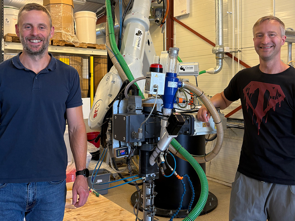 De två männen Daniel och Jonathan från CircLAB står bredvid deras 3D-printer och ser glada ut.