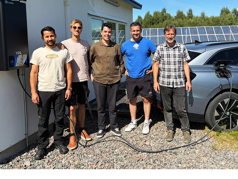 Personer framför en elbilsladdare och en elbil